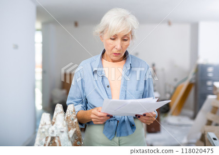 Stressed woman with papers in renovating house 118020475