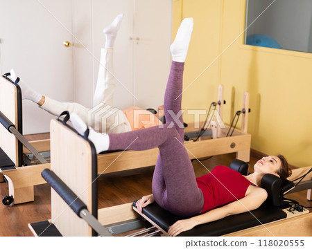 Young woman performing pilates exercises on reformer in studio Young woman performing pilates exercises on reformer in studio 118020555