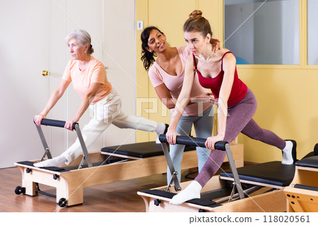 Young woman practicing pilates on reformer with female trainer 118020561