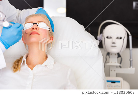 Woman getting laser facial treatment in aesthetic medicine office 118020602