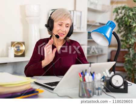 Elderly businesswoman participating in web conference at workplace in office 118020603