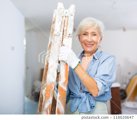 Mature woman carrying ladder, diy home renovation 118020647