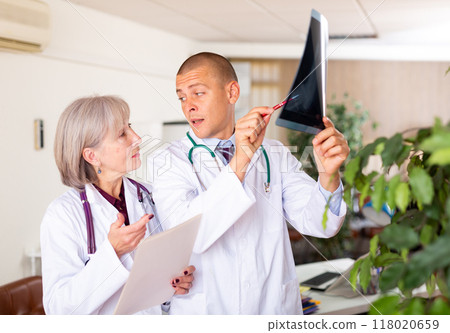 Two doctors examining x-ray of patient and discussing diagnosis Two doctors examining x-ray of patient and discussing diagnosis 118020659