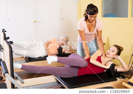Female trainer helps a woman do stretching exercises Female trainer helps a woman do stretching exercises 118020665