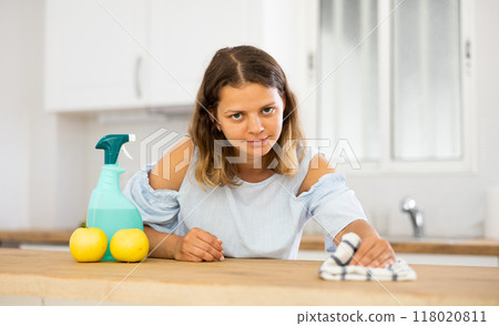 Positive housewife cleans table in home kitchen 118020811