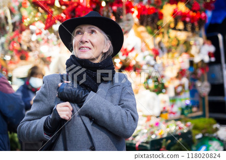 Smiling aged woman walking at traditional city christmas fair 118020824