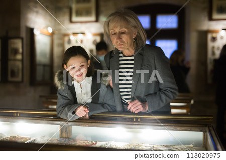 Senior woman and tween girl observing arts and crafts in museum 118020975