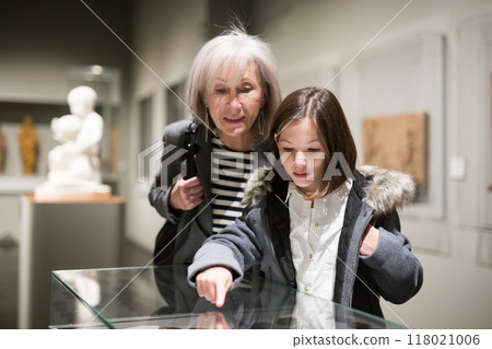 Senior woman and tween girl observing arts and crafts in museum Senior woman and tween girl observing arts and crafts in museum 118021006