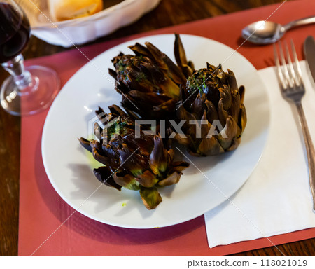 Tasty whole roasted artichokes served on plate 118021019