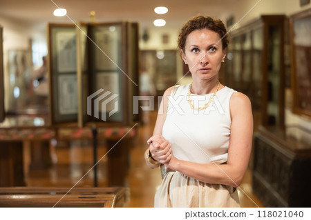Woman visit museum, examines masterpiece at exhibition 118021040