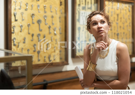 Woman with sheet piece of paper in her hands walks around museum hall 118021054
