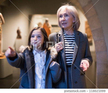 Preteen girl visiting museum of ancient sculpture her grandmother Preteen girl visiting museum of ancient sculpture her grandmother 118021099