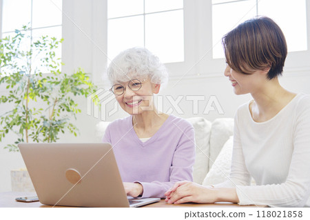 Mother and daughter using laptop in living room 118021858