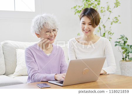 Mother and daughter using laptop in living room Mother and daughter using laptop in living room 118021859