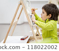 Little boy draws in studio. Art therapy, art education for children. Painting on paper on easel. Developing fine motor skills and imagination. 118022002