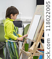 Little boy draws in studio. Art therapy, art education for children. Painting on paper on easel. Developing fine motor skills. Mock up. 118022005