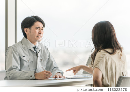 A male businessman in work clothes listening to a female customer's complaint 118022278
