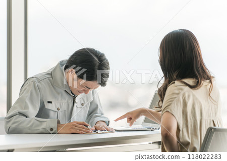 一名身穿房屋建築商/房屋承包商工作服的男性商人向一名女性顧客道歉。 一名身穿房屋建築商/房屋承包商工作服的男性商人向一名女性顧客道歉。 118022283
