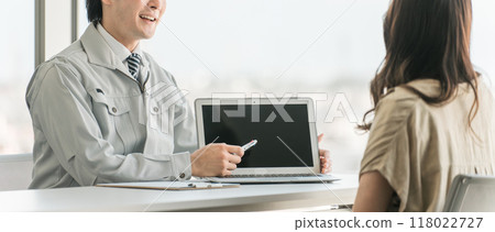 A male and female customer in work clothes using a computer to present estimates and simulations for home renovations 118022727