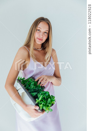 Beautiful fashion woman in silk dress and bag with green leaves Beautiful fashion woman in silk dress and bag with green leaves 118022928