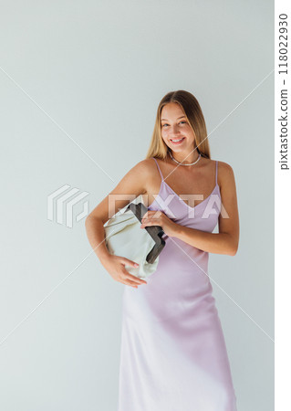 Beautiful fashionable blonde woman in silk dress holding clutch and smiling 118022930
