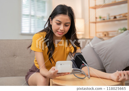 Young woman monitoring her blood pressure at home 118025665
