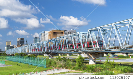 穿越多摩川的電車和川崎車站前的建築物的風景【神奈川縣川崎市～東京都大田區】 118026107