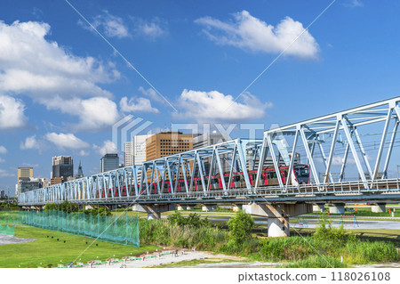 A train crossing the Tama River and the buildings in front of Kawasaki Station [Kawasaki City, Kanagawa Prefecture - Ota Ward, Tokyo] 118026108