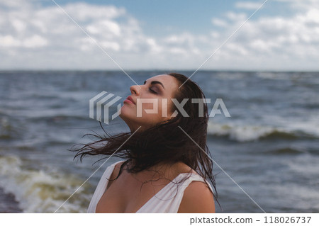 banner, portrait of brunette woman in profile looks to right with wet flying hair against background of sea banner, portrait of brunette woman in profile looks to right with wet flying hair against background of sea 118026737