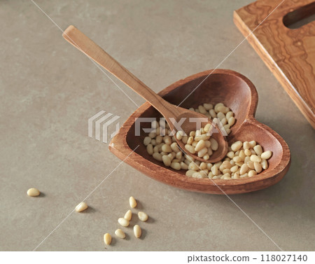 Natural pine nuts in heart shaped bowl. Wooden dishes and furniture in kitchen. Healthy products. Natural pine nuts in heart shaped bowl. Wooden dishes and furniture in kitchen. Healthy products. 118027140