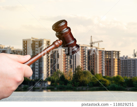 Judge's gavel against the background of residential high-rise buildings. Real estate court decisions. Property inheritance litigation. Establishment of ownership. 118029251