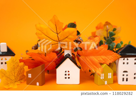 Miniature houses and autumn leaves on orange background. Autumn and real estate concept. Decor and decorations. Miniature houses and autumn leaves on orange background. Autumn and real estate concept. Decor and decorations. 118029282