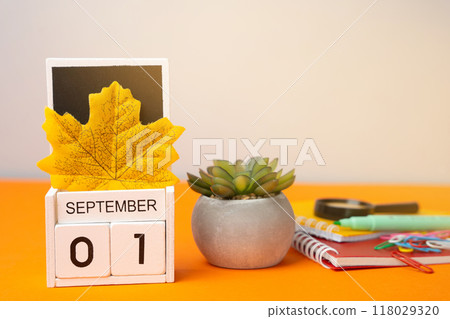 Wooden calendar with words September 1st. Beginning of the school year. New season. Notebooks, flower and yellow leaves. Wooden calendar with words September 1st. Beginning of the school year. New season. Notebooks, flower and yellow leaves. 118029320