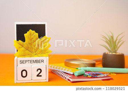 Wooden calendar with words September 2nd. Beginning of the school year. New season. Notebooks, flower and yellow leaves. Wooden calendar with words September 2nd. Beginning of the school year. New season. Notebooks, flower and yellow leaves. 118029321