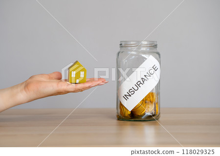 Housing insurance concept. Home, property and life Insurance. Mortgage, loan. A miniature house on a hand and a jar of coins. Business and finance 118029325