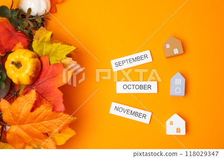 Wooden blocks September, October, November and autumn leaves on orange background with houses. Concept of beginning of new autumn season. Months of fall. Real estate 118029347