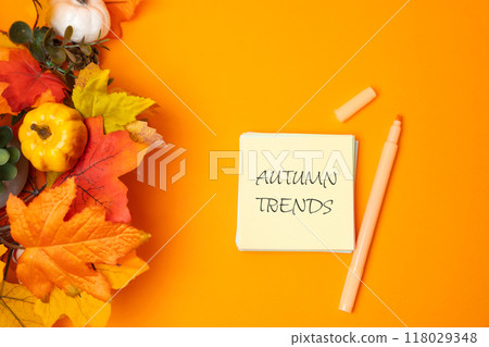 Note autumn trends and yellow leaves on orange background. Popular and relevant topics. New ideological trends of fashion. Recent and latest trend. 118029348