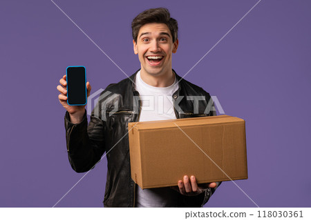 Excited smiling man, online shopping consumer received cardboard order parcel box, desired purchase. Mobile phone, smartphone mockup with copy space screen for your advertisement Excited smiling man, online shopping consumer received cardboard order parcel box, desired purchase. Mobile phone, smartphone mockup with copy space screen for your advertisement 118030361