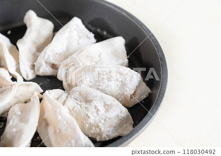 Raw dumplings arranged in a skillet 118030492
