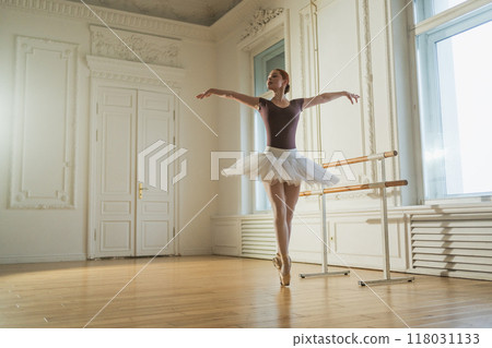 Young ballerina in tutu skirt dancing practicing ballet positions in dance class. Young classical dancer woman in dance studio. Ballet class training. Ballet school concept Young ballerina in tutu skirt dancing practicing ballet positions in dance class. Young classical dancer woman in dance studio. Ballet class training. Ballet school concept 118031133