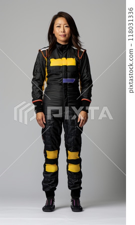 Confident female driver in black and yellow race gear standing, displaying strength and readiness for high-speed action. 118031336
