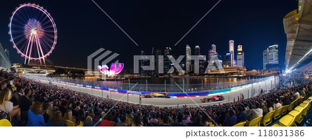 Panoramic image of vibrant nighttime scene of a Formula 1 race in a city setting. Tribune of spectators watching race event 118031386