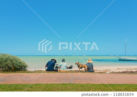 A family and a dog looking at the blue sky and blue sea on the beach in Shark Bay, Australia A family and a dog looking at the blue sky and blue sea on the beach in Shark Bay, Australia 118031654