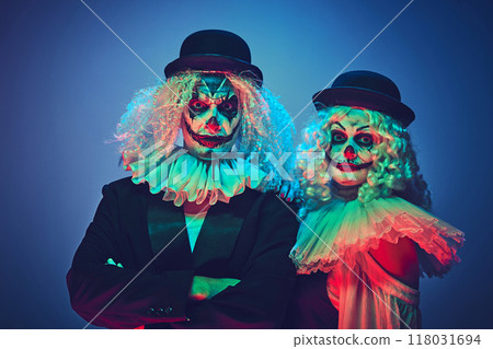 Portrait of creepy clown couple dressed retro style clothes posing looking at camera calmly in neon light against gradient background. 118031694