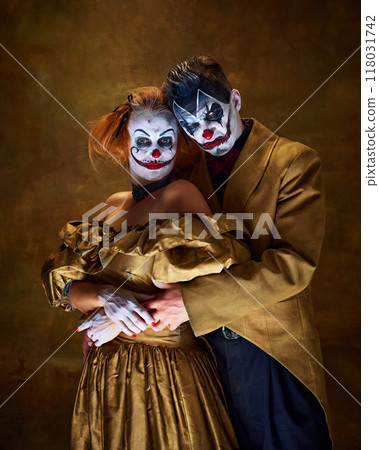 Portrait of two sinister clowns, couple dressed vintage attire hugs together against background. Mysterious and spooky. 118031742