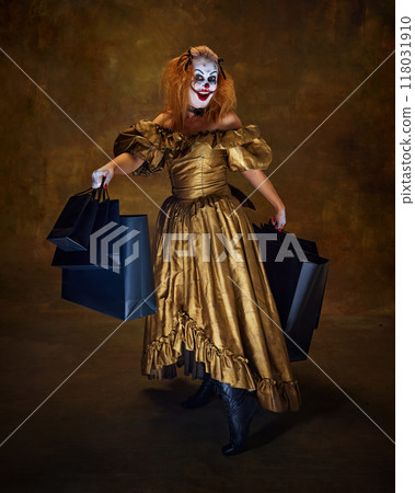 Horror-clown woman dressed in antique-style gown, holding large shopping bags, smiling wickedly, posing against vintage backdrop. 118031910