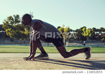 African man preparing to sprint in an athletic position outdoors African man preparing to sprint in an athletic position outdoors 118032655