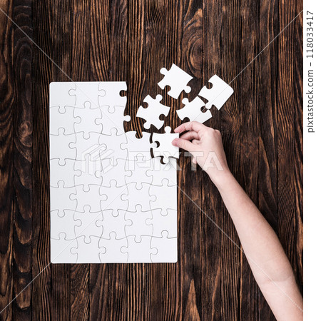 hand collecting white puzzle on brown background hand collecting white puzzle on brown background 118033417