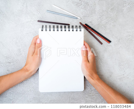 Girl's hands holding notebook Girl's hands holding notebook 118033484