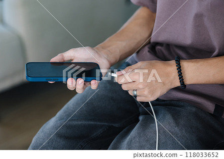 Close-up of a boy plugging in his phone to a wired charger Close-up of a boy plugging in his phone to a wired charger 118033652